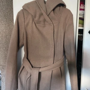 Beige kappa från Amisu - Säljer en snygg beige kappa från New Yorker i storlek EU 36. Perfekt för höst och vår när du vill hålla dig varm. Kappan är i bra skick men har knoppror. 