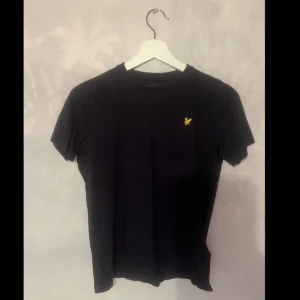Mörkblå t-shirt från Lyle & Scott Junior - Säljer en stilren mörkblå t-shirt från Lyle & Scott Junior. Den har den klassiska loggan på bröstet. T-shirten är i bra skick och passar barn i åldern 10-11 år. Perfekt för både skola och fritid!