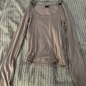 Beige långärmad topp - Säljer en beige långärmad topp i mycket bra skick. Perfekt för både vardag och festliga tillfällen. Den har en enkel och elegant design med en rund halsringning. Passar bra till jeans eller kjol 