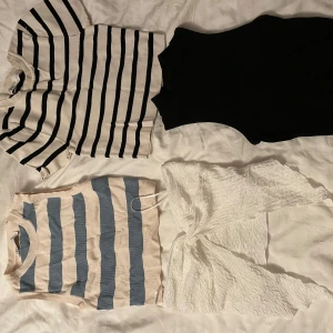 Fyra toppar i olika stilar - Säljer fyra snygga toppar! En svart ärmlös topp. Två randiga toppar, en med blå och vita ränder och en med svarta och vita ränder, båda kortärmade. Den sista är en vit, ribbad och croppad topp med öppning vid magen. Alla i bra skick. Alla för 150