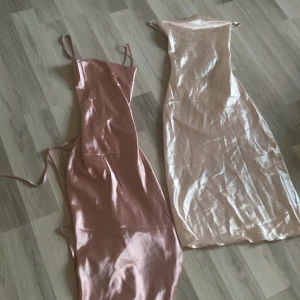Två sidenklänningar i rosa och champagne - Säljer två eleganta långklänningar i siden, en i ljusrosa och en i champagne. Båda har smala axelband och en figurnära passform. Perfekta för festliga tillfällen! ✨