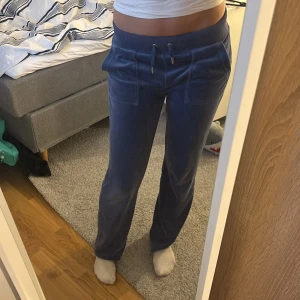 Blå juicy byxor - Säljer ett par superbekväma blå mjukisbyxor i mycket bra skick. De har en loose passform och är perfekta för mysiga dagar hemma. Byxorna har en elastisk midja med snörning och praktiska fickor med knappar bak. Perfekta för höst och vinter!