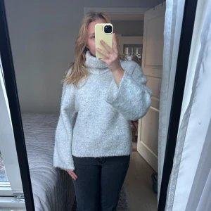 Grå stickad polotröja - Mysig grå stickad polotröja med hög krage och långa ärmar. Perfekt för kyliga dagar och ger en stilren look. Passar bra till jeans eller kjol för en avslappnad stil.