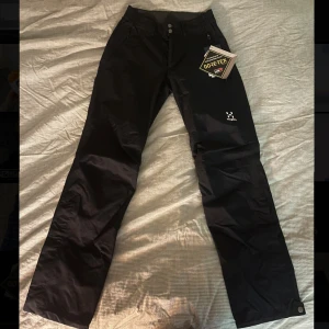 Svarta Astral GTX byxor från Haglöfs - Säljer ett par svarta Astral GTX byxor från Haglöfs i storlek S. Byxorna är tillverkade i GORE-TEX-material för att hålla dig torr. De har en rak passform med dragkedja vid bensluten och knappar i midjan. Nypris ligger runt 2000kr