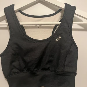 Svart sporttopp från Röhnisch - Säljer en snygg svart sporttopp från Röhnisch i storlek S. Stretchig och mjuk i materialet. Aldrig använd, så mycket bra skick!