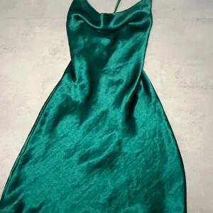 Grön satin klänning - Kort grön satin klänning som man knyter i ryggen. Använt 1 gång. Nypris 519 kr. Passar xs-m då man knyter själv