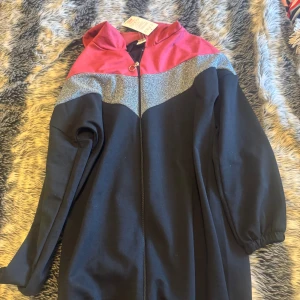 Lång jacka/Abaya - Säljer en cool svart lång jacka med röda och glittriga silverdetaljer. Den har en dragkedja framtill och en huva. Perfekt för att sticka ut lite extra! Med pris lapp kvar 🖤✨