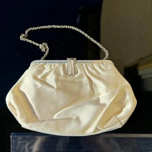 Elegant benvit festväska - Benvit söt handväska som kan användas som clutch. Väskan har en stilren design med en metallisk ram och en snygg låsdetalj på toppen. Perfekt för festliga tillfällen. Mått -se linjal på bilder. Hämtas på Hägerstensåsen eller ök 💖✨