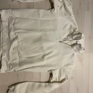 Vit tröja med dragkedja från Zara - Säljer en stilren vit half zip tröja från Zara i storlek S. Tröjan har en praktisk dragkedja vid halsen och är perfekt för både vardag och avslappnade tillfällen. Materialet känns mjukt och bekvämt, vilket gör den idealisk för höst och vår.