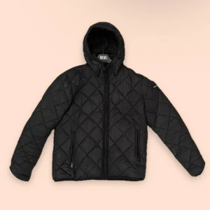 Svart quiltad jacka från Jofama - Säljer en snygg svart quiltad pufferjacka från Replay. Den har en dragkedja framtill och en mysig huva. En favorit som jag älskar. Litet hål i vänstra arm. Jackan är i toppen skick.