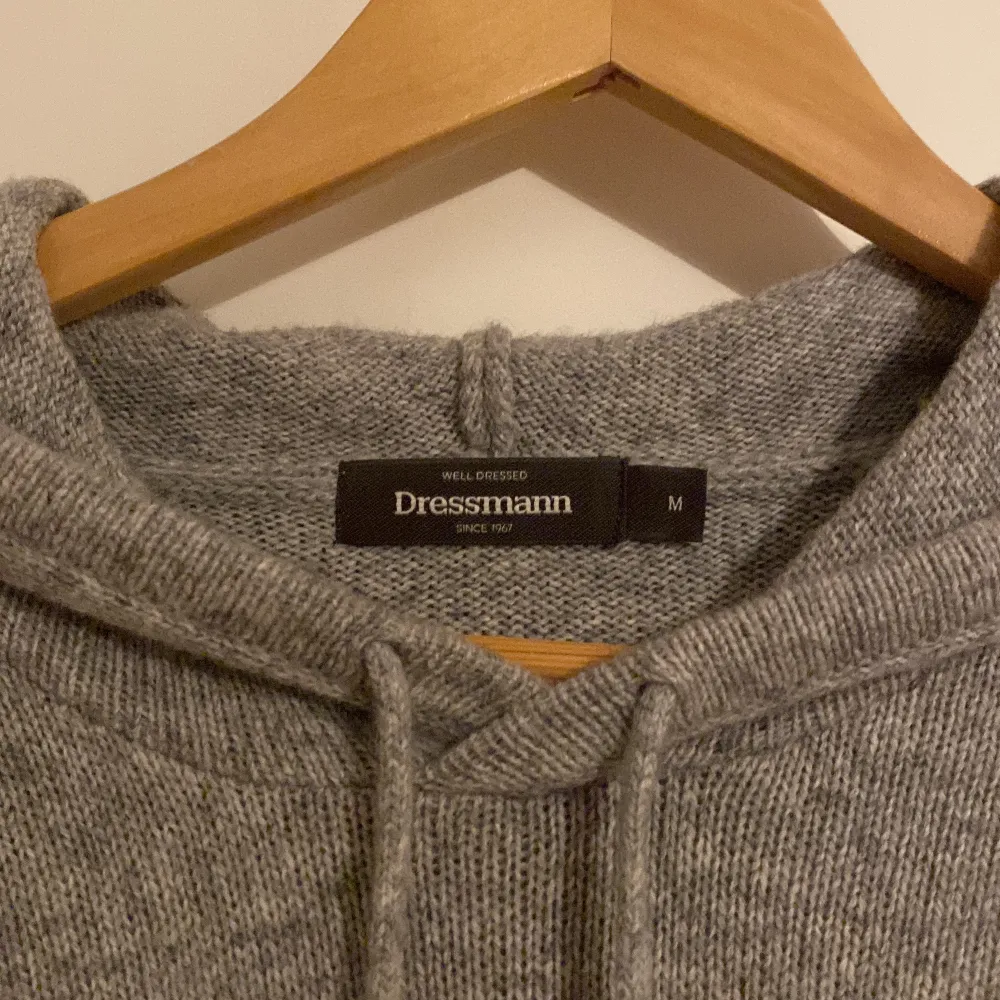 Säljer en supermysig grå stickad hoodie från Dressmann. Perfekt för kyliga dagar med sin mjuka och varma känsla. Den har en klassisk passform med långa ärmar och en praktisk huva med snörning. Perfekt för både vardag och avslappnade tillfällen!. Tröjor & Koftor.