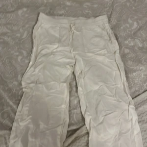 Vita byxor med dragsko - Säljer ett par vita byxor med dragsko i midjan. Byxorna har en loose passform och är tillverkade i ett mjukt material. Perfekta för en avslappnad stil.