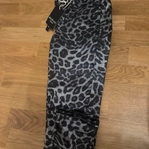 Leopardmönstrade byxor från Redial - Snygga leopardmönstrade byxor från Redial med en cool look. Byxorna har en elastisk midja med snörning för extra komfort. Perfekta för att sticka ut med ett djärvt mönster.