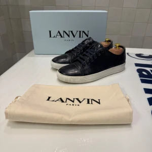 Blåa  sneakers från Lanvin - Snygga blåa  sneakers från Lanvin med vit sula och klassisk snörning. Skorna har en stilren design och är perfekta för en avslappnad stil. Endast skorna ingår och de är U.S. 9 vilket motsvarar runt storlek 44