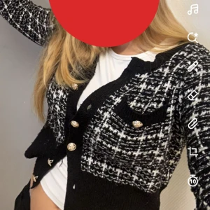 Svartvit kofta med knappar - Snygg svartvit kofta med ett rutigt mönster och dekorativa knappar. Perfekt för att ge en stilren touch till din outfit. Koftan har långa ärmar och en klassisk design. 