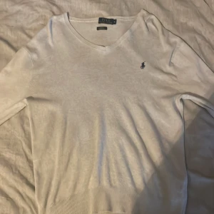 Beige tröja från Polo Ralph Lauren - Säljer en stilren beige tröja från Polo Ralph Lauren i pima bomull. Tröjan har en v-ringad design och ett broderat logotypmärke på bröstet. Perfekt för en klassisk, avslappnad och fräsch look.