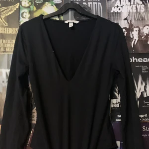 Svart långärmad Body topp från H&M - Säljer en stilren svart långärmad topp från H&M med v-ringning. Perfekt för en enkel och elegant look. Passar bra till både jeans och kjol. (Det är en body)
