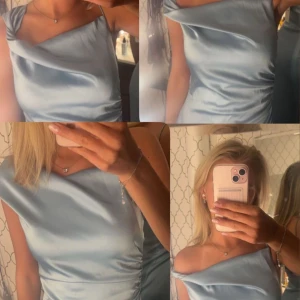 Ljusblå sidenklänning från adoore - Elegant ljusblå klänning i siden med en stilren oneshoulder-design. Klänningen har en smickrande passform med slits och subtila rynkdetaljer på sidan. Perfekt för speciella tillfällen. Den är från adoore och har lapp kvar och  den är aldrig använd. Köpte den till midsommar i början på förra sommaren men använde den aldrig så den har bara hängt i min garderob. Passar perfekt till bal eller lite finare tillfällen. Nypris är 1600kr 