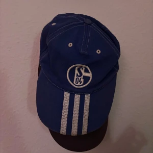 Blå keps från Adidas med Schalke 04-logga - Snygg blå keps från Adidas med Schalke 04-logga framtill. Nästintill oanvänd, och justerbar så passar alla!!🙌