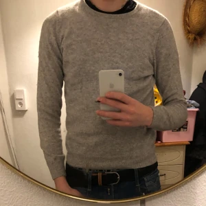 Grå kashmirtröja från Davida - Säljer en stilren grå kashmirtröja från Davida. Tröjan har en klassisk design med långa ärmar och rund halsringning. Perfekt för att hålla sig varm och bekväm under kyligare dagar. Passar utmärkt till både jeans och mer uppklädda outfits. Storlek är s men skulle säga att den passar bättre på xs och då om du är vid 172