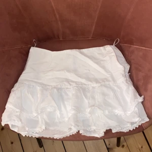 Vit kjol med volangdetaljer - Söt vit kjol från Zara med volangdetaljer och dragkedja i sidan. Dragkedjan är dock trasig, men om man har en lång tröja så syns det inte Perfekt för en somrig look. Kjolen har en kort längd och är gjord i ett lätt material. 