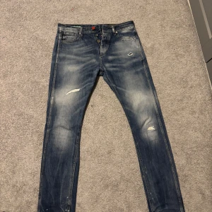 Blå jeans med slitningar från Jack and Jones  - Säljer min killes Snygga blå jeans med en cool slitningseffekt och en anti fit-stil. De har en klassisk femficksdesign och en knappgylf. Perfekta för en avslappnad look med en touch av edge. Dom är i fint skick, skriv vid funderingar🤍