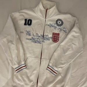 En fet zip hoodie i S - Vit zip hoodie med fet tryck och är i bra skick. Köpt på Vinted men var för liten för mig därför jag säljer i storlek S.