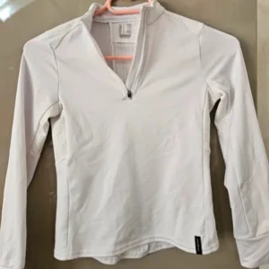 Vit långärmad tröja med dragkedja - Säljer en stilren vit långärmad tröja med dragkedja framtill. Perfekt för kyligare dagar eller som ett lager under jackan. Tröjan är i bra skick och har en bekväm passform. Passar både till vardags och träning! Köpt från Decathlon för 299kr. Fleece!