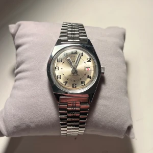 Ruhla vintage klocka 1970-tal - Säljer ett antimagnetic Ruhla armbandsur med silverfärgad/champagn urtavla och silverfärgat armband.  Fungerar men går något långsamt. Uret är i gott skick med några små repor på glaset och armbandet. Säljes i befintligt skick. Mekanisk rörelse. 