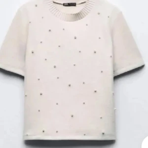 Vit tröja med pärlor från Zara - Säljer en superfin vit tröja från Zara med korta ärmar och dekorerad med små pärlor över hela framsidan. Perfekt för en stilren och elegant look. Tröjan är i ett mjukt material och har en normal passform. Perfekt för både vardag och fest!