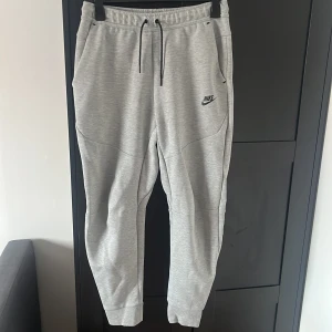 Grå Nike Tech Fleece byxor  - Säljer mina gråa Nike Tech Fleece byxor som är köpta för ungefär 4-5 år sen när jag var yngre (15-16 år) och är aldrig använda. Köpta på JD sports men föräldrarna hittar ej kvittot. (Köpta som set med hoodien, original priset var runt 1000-1200kr)
