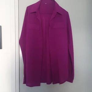 Lila skjorta med fickdetaljer - Säljer en snygg lila skjorta med långa ärmar och stilrena fickdetaljer på bröstet. Perfekt för både vardag och fest! 💜