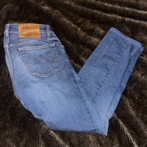 Säljer ett par snygga blå jeans från Jacob Cohën i storlek 31. De har en klassisk femficksdesign och en snygg broderad detalj på den lilla fickan. Jeansen är i mycket bra skick och har en knappgylf. Perfekta för både vardag och fest!