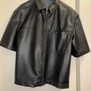 Svart skinnjacka med korta ärmar - Säljer en iskall skinnjacka me korta ärmar. Köpt i Porto på Zara. Använd till en youtube video endast. Storlek Small. 