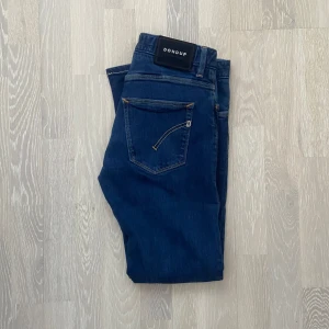 Blå jeans från Dondup - Säljer ett par snygga blå jeans från Dondup i lyxigt denim. De har en slim och bekväm passform med en skönt strechigt material. Längd: 91cm, Bredd: 37cm. Hör av er vid frågor och funderingar!
