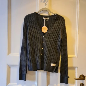 Svart ribbad kofta från Odd Molly - Säljer en snygg svart ribbad kofta från Odd Molly i storlek S. Den har en v-ringad design med knappar framtill och är i ett mjukt och bekvämt material. Perfekt för både höst och vinter! Helt oanvänd med prislapp kvar - vintage 🖤