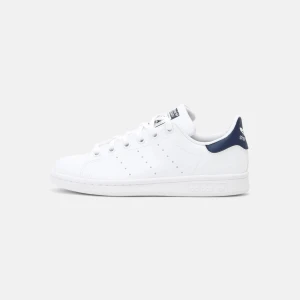 Vita Adidas Stan Smith sneakers - Säljer ett par klassiska vita Adidas Stan Smith sneakers i snyggt och stilrent utförande. Skorna har en vit bas med mörkblå detaljer på hälen och är perfekta för både vardag och fest. De är i mycket bra skick och passar till alla outfits, endast använda ett fåtal gånger! 