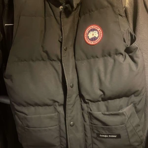 Svart dunväst från Canada Goose - Säljer en svart Canada Goose väst i storlek S i mycket bra skick. Västen är använt några gånger här & där och den har inga skador alls, köpt den för 6 tusen, den är i mycket bra skick så därför säljer jag den för 5 tusen men pris kan diskuteras!💕