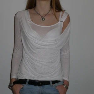 Vit glittrig topp - Superfin vit glittrig topp med långa ärmar och en unik omlott-design. Passar storlek S-M.