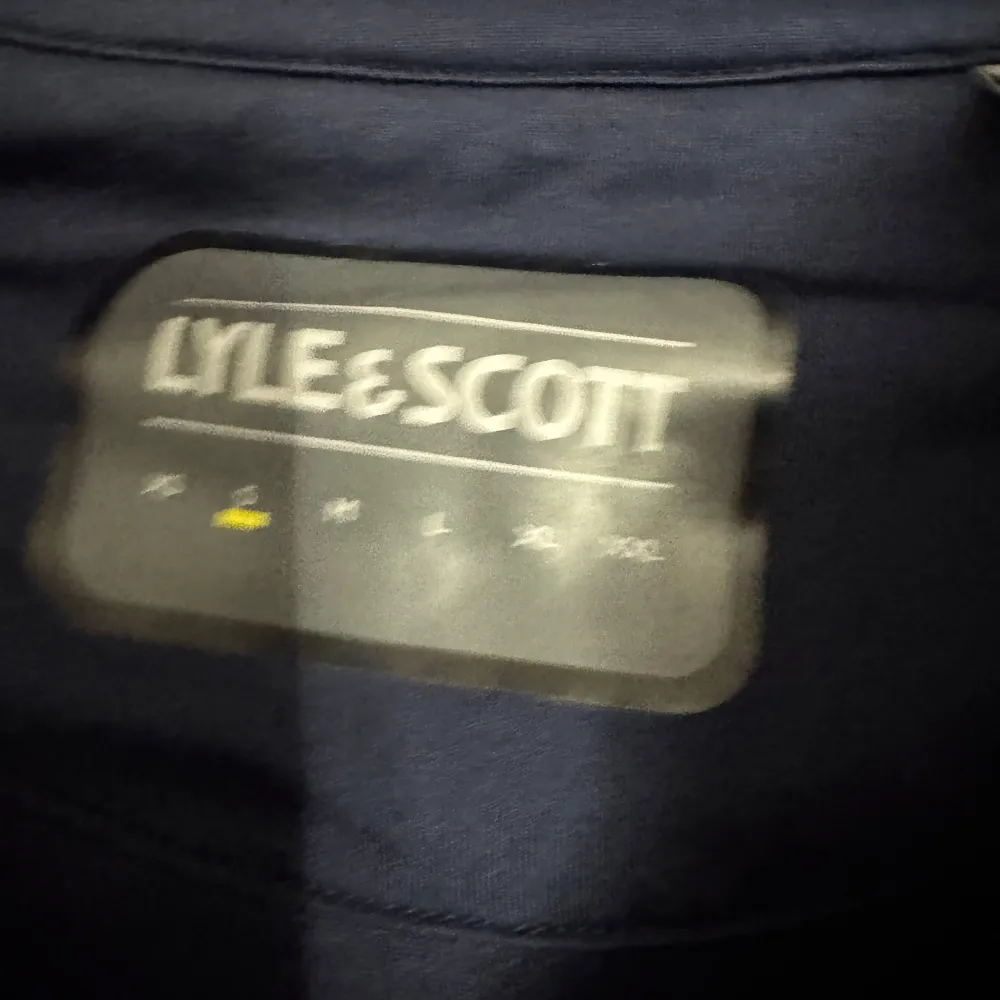 Säljer en snygg mörkblå hoodie från Lyle & Scott. Den har en dragkedja framtill och en klassisk gul logga på bröstet. Perfekt för höst och vår, med långa ärmar och en bekväm passform. Huvan har snören för justering. Perfekt för en casual look! Köpt för 900kr pris kan såklart diskuteras!. Tröjor & Koftor.