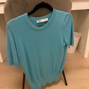 Turkos tröja från Zara - Säljer en snygg turkos tröja från Zara i storlek S. Den har en enkel och stilren design med korta ärmar och rund halsringning. Perfekt för både vardag och festliga tillfällen. Tröjan är i mycket bra skick och redo för en ny ägare!