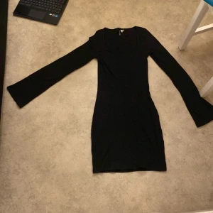 Svart ribbad klänning från H&M Divided - Snygg svart ribbad klänning från H&M Divided i storlek S. Den har en tight passform och långa ärmar, perfekt för både vardag och fest. Klänningen är i mycket bra skick och passar utmärkt till höst och vinter. Enkelt att styla med olika accessoarer!