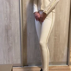 Beige leggings från Chiara Ferragni - Snygga beige leggings från Chiara Ferragni i nytt skick. De är tighta och har en stilren design med en guldfärgad dragkedja längs sidan. Perfekta för både vardag och fest! 🥳