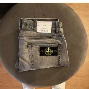 Grå jeans från Stone Island - Säljer ett par grå jeans från Stone Island i bra skick ca 7/10. De är i storlek 32 i midjan och 32 i längden men skulle nog säga att de är lite mindre i passformen. Byxorna är äkta! Mvh Oscar 