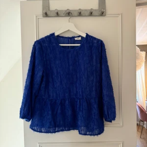 Blå blus med blå fina smådetaljer - Supergullig blå blus med blå detaljer. Den har trekvartsärmar och en luftig passform🩵 Blusen har också en liten knapp i nacken för enkel på- och avtagning. Endast använd några gånger så är bra skick🤍