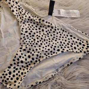 Prickig bikiniunderdel från Lindex - Säljer en superfin prickig bikiniunderdel från Lindex i storlek XS. Den är vit med svarta prickar och har en klassisk passform. Perfekt för sommarens alla stranddagar! Helt ny med tag kvar. 🖤🤍