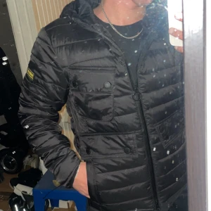 jacka från Barbour international  - Säljer en snygg svart pufferjacka från Barbour i storlek S. Jackan har en dragkedja och knappar framtill, samt flera praktiska fickor. Perfekt för kyliga dagar med sin quiltade design. Den är i mycket bra skick och säljs då den ej kommit till användning. Nypris 4300kr