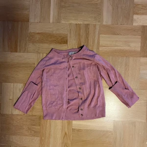 Rosa kofta från H&M - Säljer en söt rosa kofta från H&M i storlek S. Den har långa ärmar och knappar framtill. Perfekt för både vår och höst, och den är supermjuk och bekväm att ha på sig. Passar till både jeans och kjol!