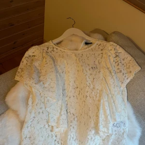 Vit spetsblus från Gina Tricot - Säljer en superfin vit spetsblus från Gina Tricot i storlek 34. Aldrig använd, endast testad. Blusen har korta ärmar och ett vackert blommigt spetsmönster.💝💘🩷