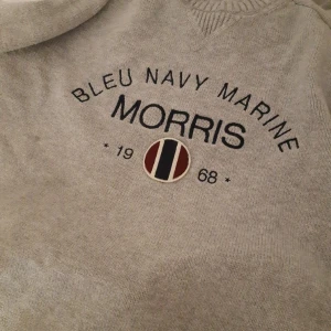 Grå tröja från Morris - Säljer en snygg grå tröja från Morris med texten 'Bleu Navy Marine' och årtalet 1968 tryckt på framsidan. Perfekt för en avslappnad stil med en touch av klass. Tröjan är i bra skick och passar perfekt till både vardag och fest.
